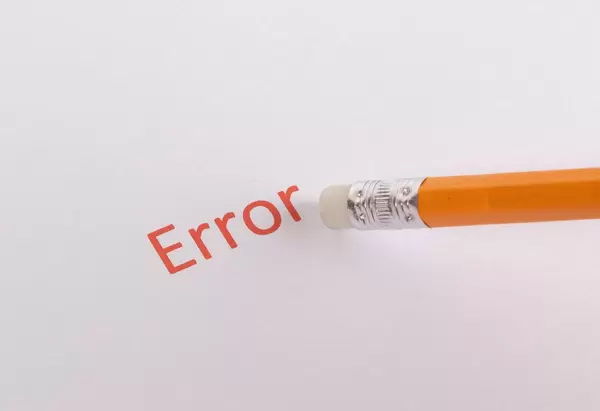 Ein Radiergummi auf einem Bleistift radiert das rote Wort Error auf weißem Hintergrund