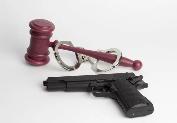 Ein Richterhammer mit Handeschellen und einer Pistole