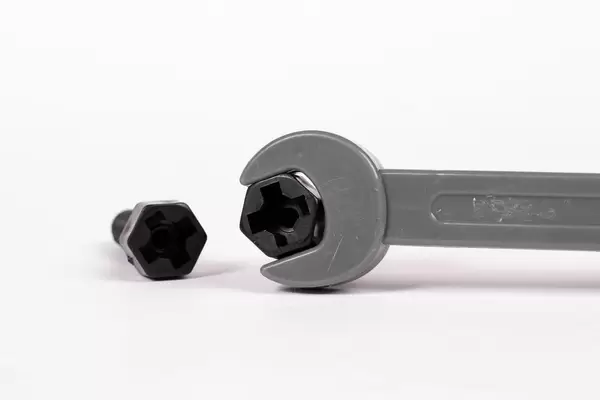 Ein Schraubenschlüssel packt eine Schraube auf weißem Hintergrund