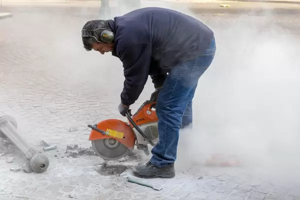 Ein Straßenarbeiter schneidet mit einer Steinsäge in den Gehweg in Venlo