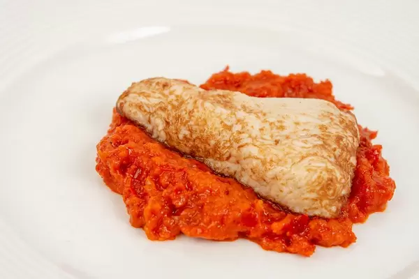 Ein Stück Hähnchenbrust in Chilisoße liegt auf dem Paprika Ajvar Dip