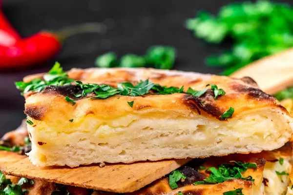 Ein Stück Käse Khachapuri auf einer hölzernen Spachtel