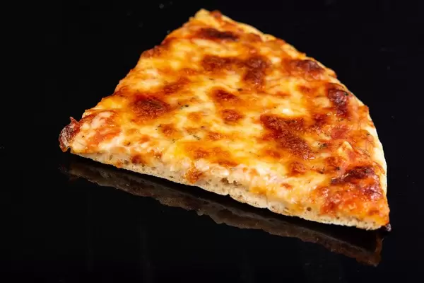 Ein Stück Pizza Margherita spiegelt sich auf schwarzem Hintergrund