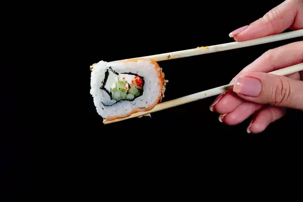 Ein Stück Sushi mit Essstäbchen gehalten