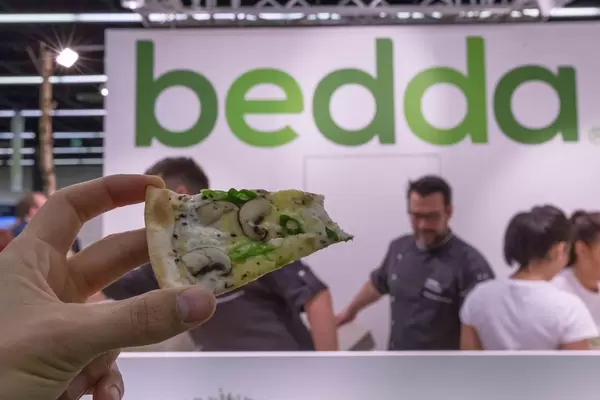 Ein Stück veganer Flammkuchen mit Pilzen und Bedda Käse