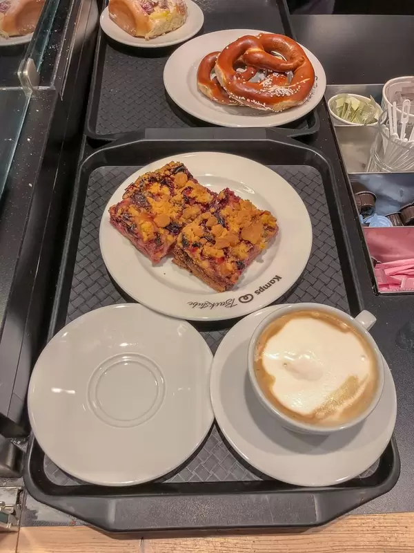 Ein Tablet mit einer Tasse Cappuccino und Pflaumen-Streuselkuchen