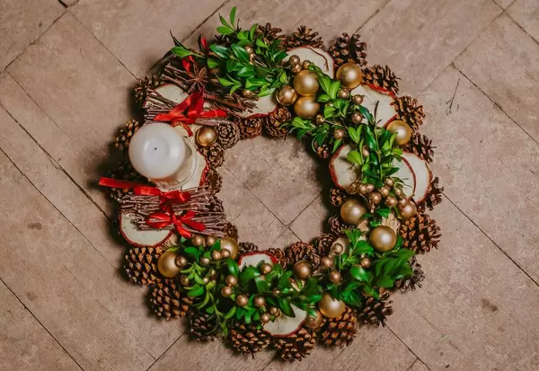Ein Weihnachtskranz mit Mistelzweigen, goldenen Kugeln, Tannenzapfen und einer Kerze