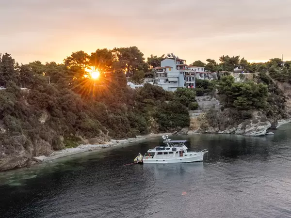 Ein weißes Boot ruht vor den Häusern von Skiathos, Thessalien, bei Sonnenuntergang
