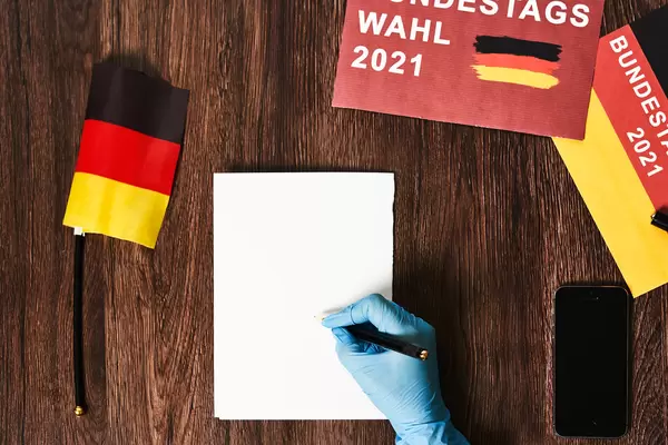 Ein Wer in medizinischen Handschuhen fas Bulletin in der Wahlkabine aus