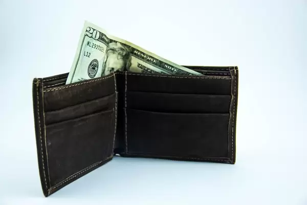 Ein zwanzig Dollarschein guckt aus einem dunkel brauen Lederportemonnaie heraus