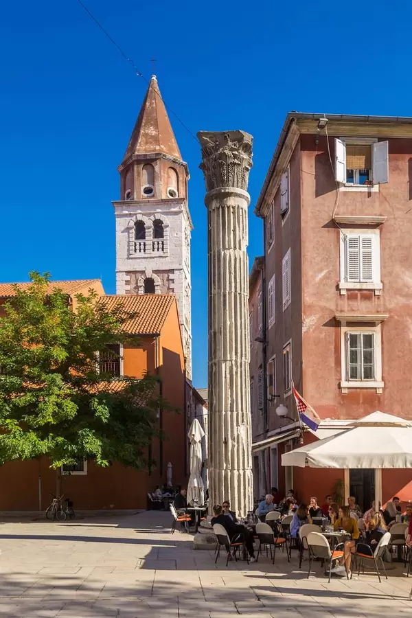 Eine antike römische Säule mit einer Kirche im Hintergrund in Zadar, Kroatien