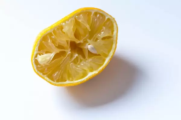 Eine ausgepresste Zitrone vor weißem Hintergrund