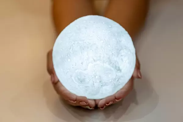 Eine Dame hält einen hell leuchtenden Mond in der Hand