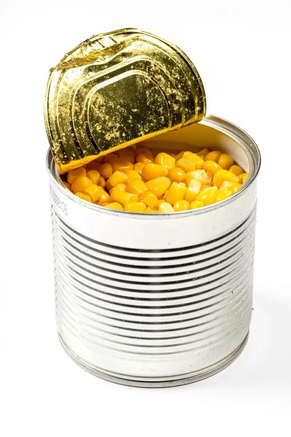 Eine Dose aus Metall mit Mais vor weißem Hintergrund