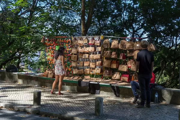 Eine Frau betrachtet die aus Kork gefertigten Handtaschen eines Souvenirstandes