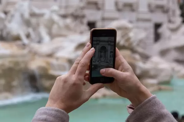 Eine Frau macht ein Foto mit dem iPhone von Statuen in Rom