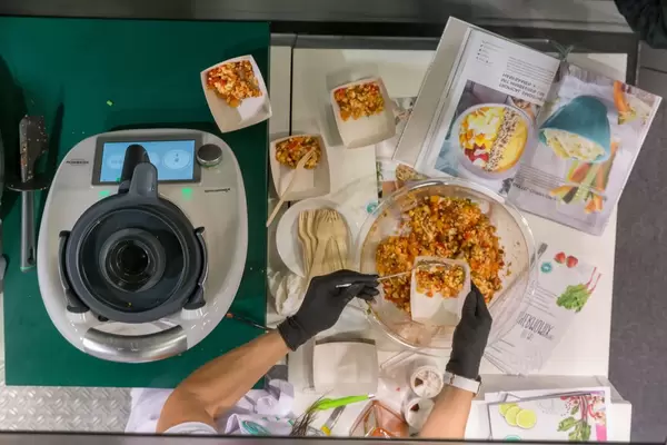 Eine Frau vorbereitet ein Gemüse-Gericht mit Hilfe des neuen Thermomix TM6 an der Fibo Fitnessmesse