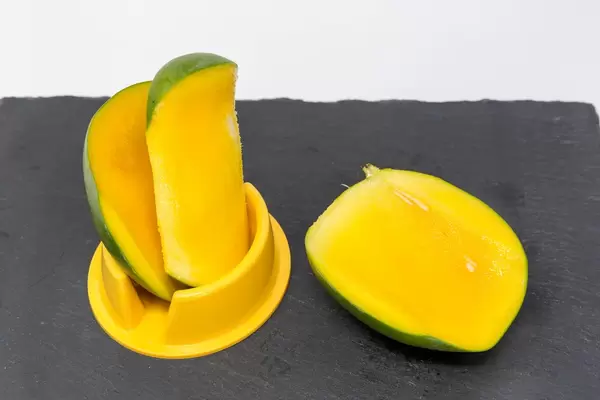 Eine frisch entsteinte Mango auf Schieferplatte