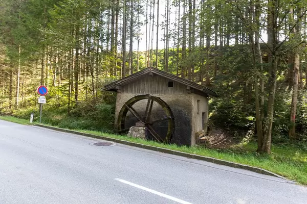 Eine funktionierende Wassermühle mit Wasserrad am Straßenrand in Tirol (Österreich)