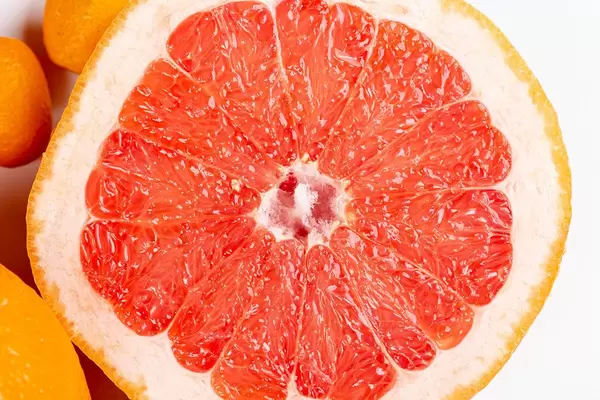 Eine halbe Grapefruit vor weißem Hintergrund in Nahaufnahme