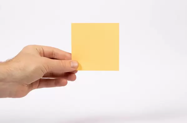 Eine Hand hält ein Notizblatt