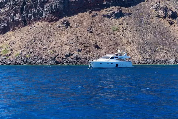 Eine Jacht, das Meer und die steile vulkanische Küste Santorinis