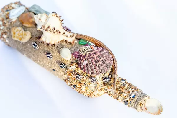 Eine mit Muscheln dekorierte Flasche auf weißem Hintergrund