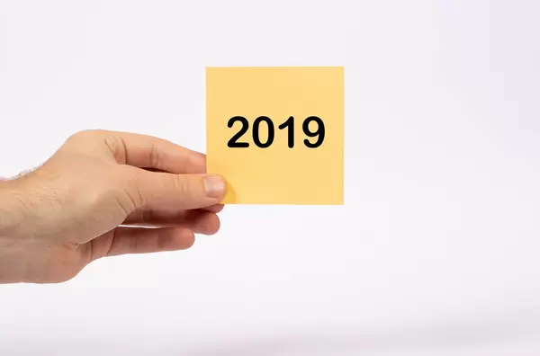 Eine Notiz mit der Aufschrift 2019 in der Hand gehalten auf weißem Hintergrund