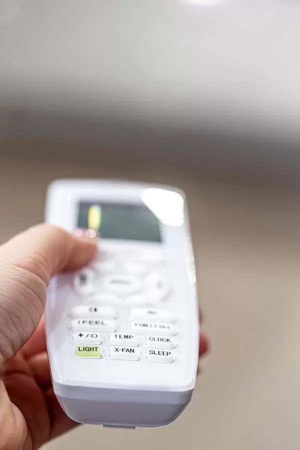 Eine Person hält eine Fernbedienung einer Klimaanlage Nahaufnahme