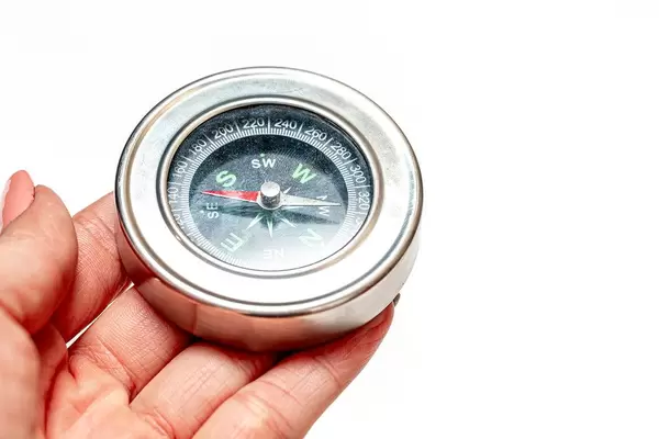 Eine Person hält einen Taschenkompass vor weißem Hintergrund