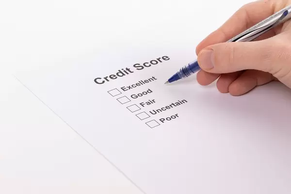 Eine Person mit Kugelschreiber wählt ein Kreditscore-Ergebnis auf einem Papier aus