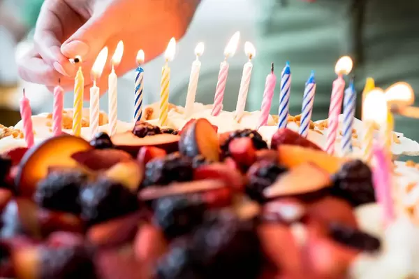Eine Person zündet Kerzen auf einem Obstkuchen an