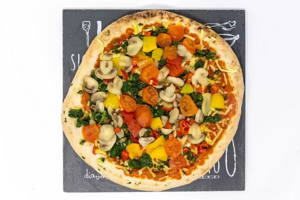 Eine Pizza mit frischem Gemüse - Pilze, Kirschtomaten, Spinat und Parpika - Nahaufnahme