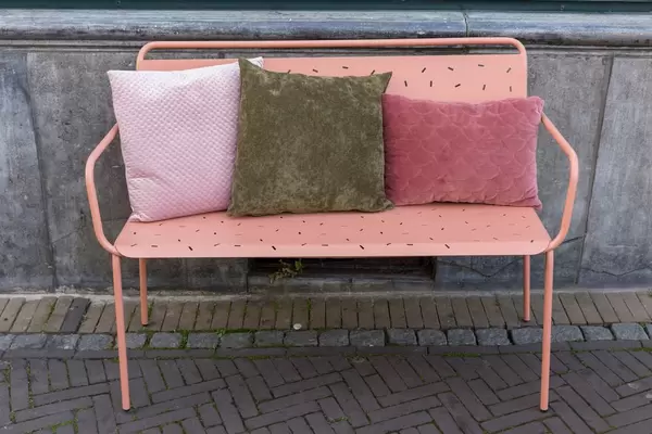 Eine rosafarbene Bank aus Metall mit Velourkissen in Venlo
