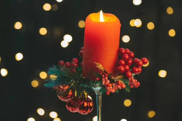 Eine rote Adventskerze zur Weihnachtszeit, vor dunklem Bokeh-Hintergrund
