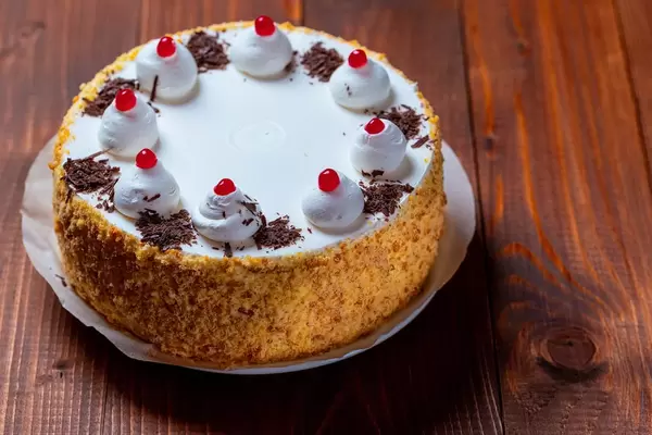 Eine Sahnetorte mit kandierten Kirschen auf hölzernem Hintergrund