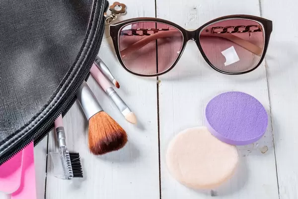 Eine Schminktasche mit Schminkpinseln und Make-Up-Pads mit einer Sonnenbrille