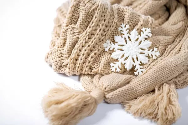 Eine Schneeflocke auf beigem gestricktem Schal