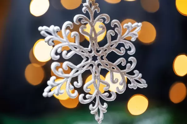 Eine Schneeflocke vor dunklem mit funkelnden Lichtern bestücktem Hintergrund