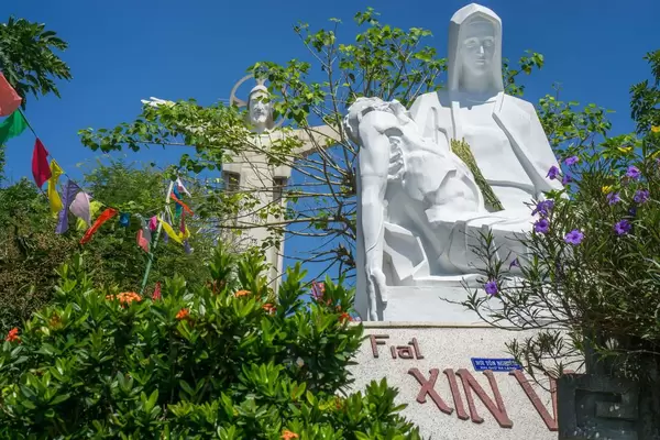 Eine Statue der heiligen Maria mit dem Jesus Christus Monument im Hintergrund in Vung Tau