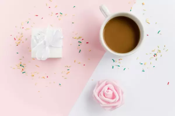 Eine Tasse Kaffee, Geschenkbox und bunte Streusel von oben fotografiert