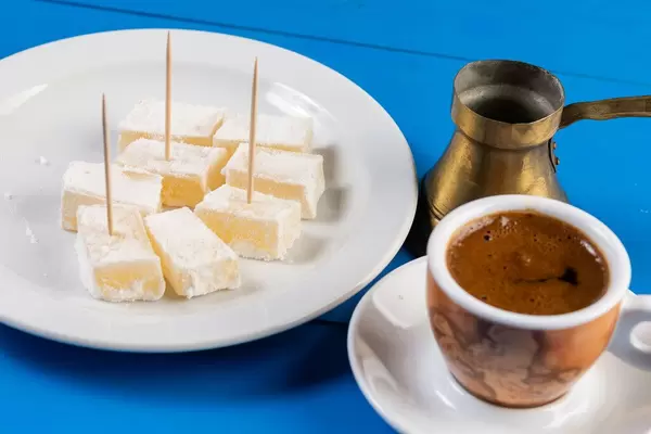 Eine Tasse Kaffee mit türkischer Kupfer-Karaffe und Lokum, Turkish Delight, auf einem blauen Holztisch