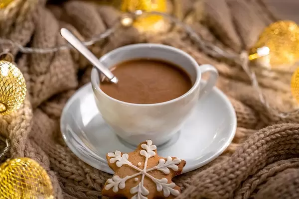 Eine Tasse Kaffee mit Weihnachtsplätzchen in Sternenform