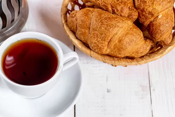 Eine Tasse Tee mit Croissants in einem Korb
