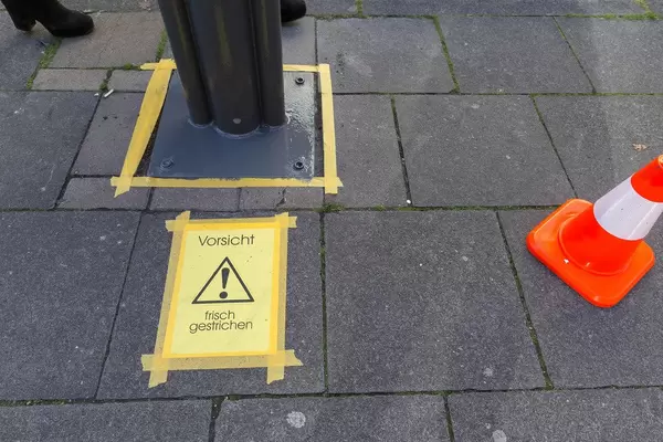 Eine Warnung vor frisch gestrichenen Pfeiler auf Bürgersteig mit Warnhütchen