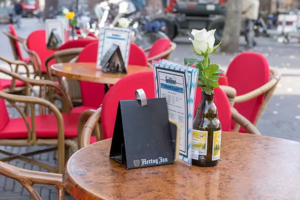 Eine weiße Rose in einer leeren Flasche Bier auf dem Tisch in einem Biergarten