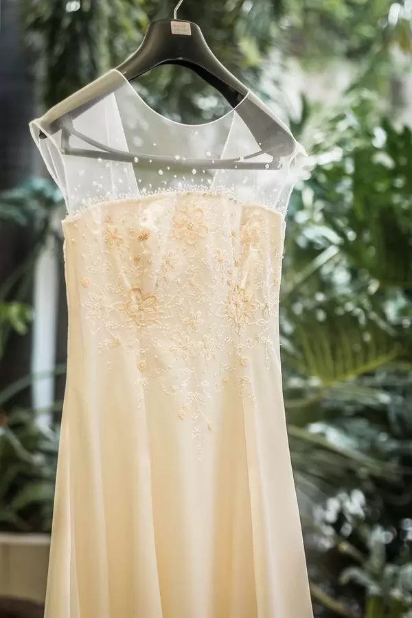 Einfaches, weißes Brautkleid mit Tüll und Stickereien vor Hintergrund aus Blättern