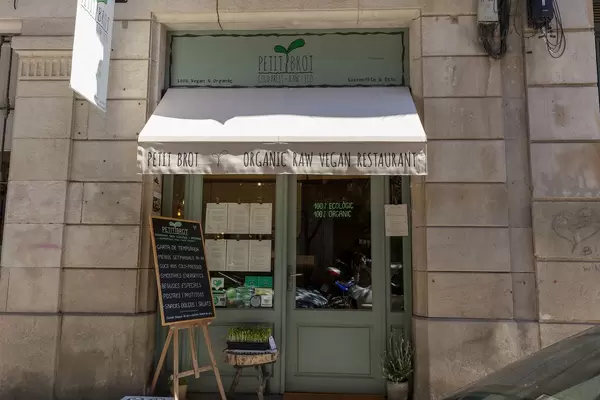 Eingang des veganen Bio-Restaurants "Petit Brot" mit Kreidetafel vor grüner Haustür an der Carrer del Dr. Dou, nahe der Kathedrale von Barcelona, Spanien