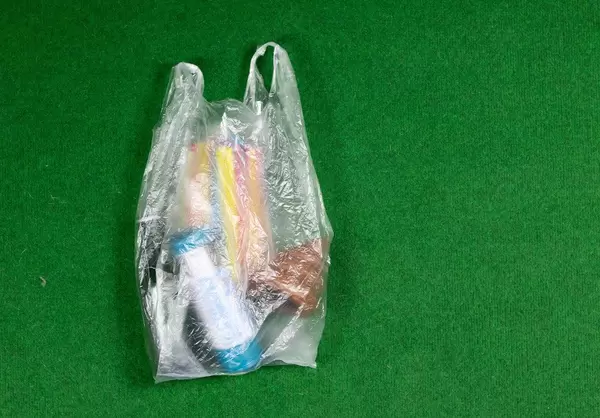 Einkauf in einer Plastiktüte auf grünem Hintergrund