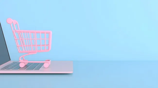 Einkaufskorb auf Laptop vor blauem Hintergrund